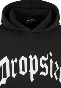 Svart hettegenser laget av myk bomull, med stor hvit gotisk stil tekst "Dropsize" på forsiden. Etiketten viser størrelse som stor.