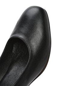 Zapato de cuero negro con un acabado liso y texturizado, punta redondeada y un diseño bajo sin hardware o acentos visibles.