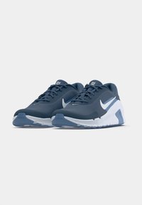 Chaussures de sport bleu foncé avec une tige en mesh texturé et des accents blancs. Dotées d'une semelle coussinée et d'un logo swoosh proéminent sur le côté.