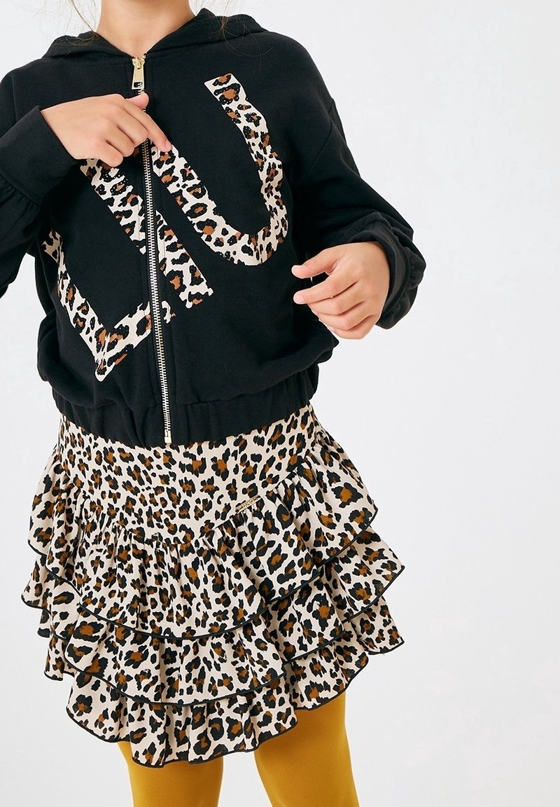 Black zip-up hoodie with a leopard print 'U' design, paired with a tiered leopard print ruffled skirt and mustard yellow tights.