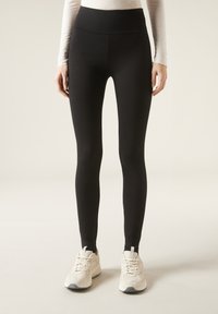 Leggings neri a vita alta realizzati in un tessuto elastico, design aderente, con una texture liscia e senza pattern o accenti visibili.