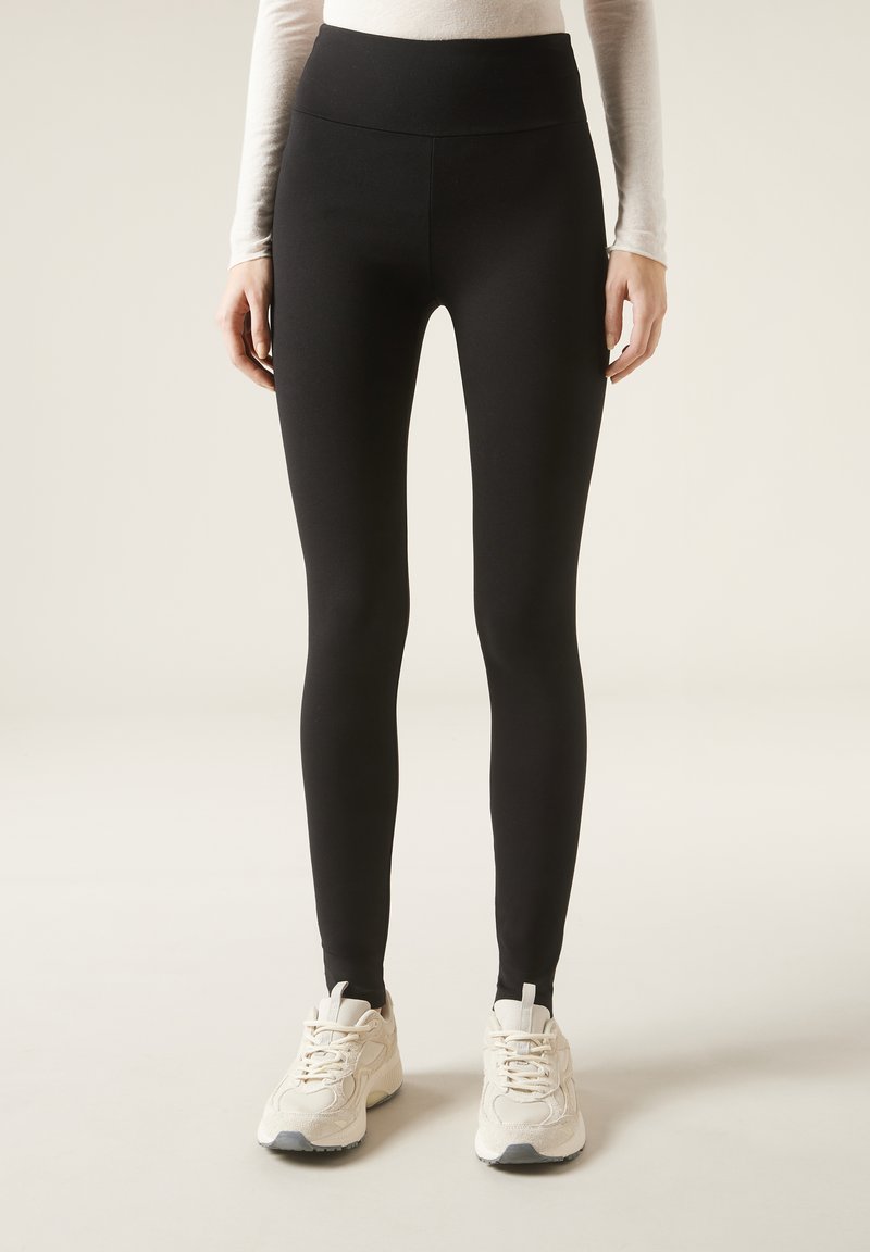 Leggings neri a vita alta realizzati in un tessuto elastico, design aderente, con una texture liscia e senza pattern o accenti visibili.