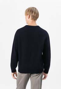 Pull en tricot bleu marine avec un col rond, des poignets et un ourlet côtelés. Texture douce, coupe décontractée et design minimaliste sans motifs ni accents.