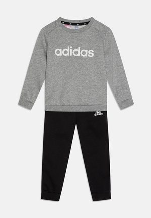 Sweatshirt gris avec le logo "adidas" blanc, associé à un pantalon de jogging noir arborant un petit logo blanc. Les deux articles sont en coton doux.