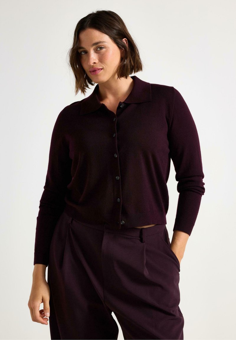 Strikket, mørk burgundy cardigan med krave, frontlukning med knapper og lange ærmer, parret med matchende højh beansede bukser.