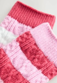 Mjuka stickade strumpor med breda horisontella ränder i röd, rosa och vit, med ribbade kanter och en fluffig textur.