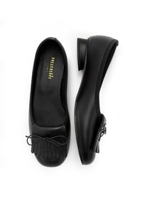 Ballerine in pelle nera con punta arrotondata, tacco basso e un fiocco decorativo con dettagli frangiati sulla punta.