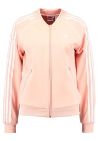 Růžová sportovní bunda na zip, s žebrovanými manžetami a spodním lemem, vybavená bílými bočními pruhy a vyšívaným logem na hrudi.