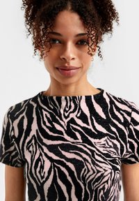 Roze en zwarte zebrapatroon shirt met korte mouwen. Strak ontwerp met een ronde halslijn, zachte structuur en gladde brei-stof.
