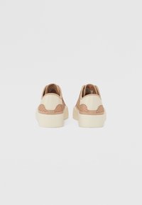 Scarpe in tessuto intrecciato di colore beige con accenti in beige più chiaro e dettagli texturizzati. Suola in gomma spessa di colore bianco sporco. Progettate per essere indossate facilmente.