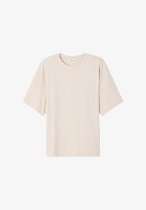 Beżowa, oversize koszulka z krótkim rękawem, o okrągłym dekolcie i gładkiej tkaninie, ułożona płasko na białym tle.