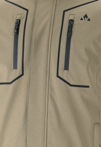 Ljusbrun jacka med svarta detaljer; har två blixtlåsfickor och geometriska sömnadsdetaljer på bröstet. Hållbar tygekvalitet.