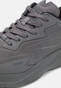 Gros plan sur une sneaker grise Hugo présentant un tissu texturé, des lacets ton sur ton, des coutures détaillées et une épaisse semelle en caoutchouc.