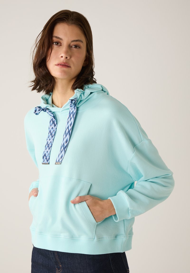 Hellblaue Kapuzenpullover mit einer Vordertasche, ausgestattet mit gemusterten Kordeln und gerippten Manschetten. Weiche Textur und lockere Passform.