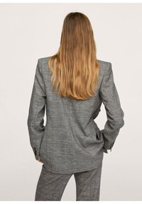 Szara marynarka w kratę z wyraźnie zaznaczonymi ramionami i długimi rękawami, z mankietami na guziki i dopasowanym krojem, widoczna od tyłu.