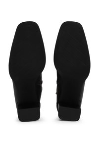 Botines de cuero negro con un acabado liso, puntera cuadrada y tacón bajo en bloque; la suela de goma presenta un patrón de banda de rodadura diagonal para mayor agarre.