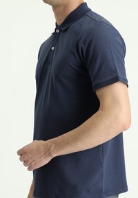 Polo shirt blu navy realizzato in cotone liscio, con colletto classico, patta con due bottoni e maniche corte. Logo discreto all'orlo.