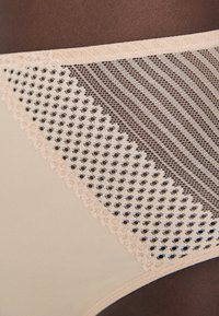 Beige underwear featuring a mesh panel with a diamond pattern, trimmed with lace; smooth texture contrasted by open weave.