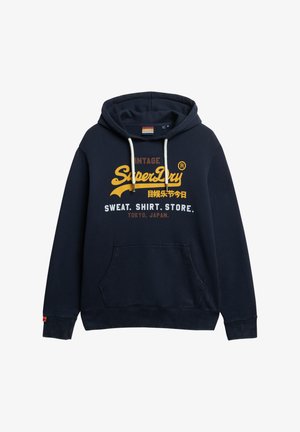 Marineblå hættebluse lavet af bomuldsblanding, med en frontlomme, snorhætte og gul grafisk tekst inklusive "SuperDry" logo.