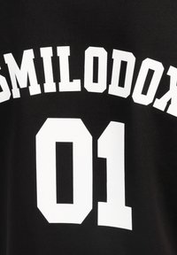 Una camiseta negra con un atrevido texto en blanco que dice "SMILODON" y el número "01", mostrado de forma prominente en la parte de atrás.