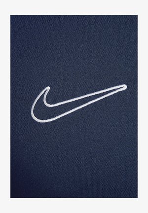 Marineblauer Stoff mit glatter Textur, mit einem weißen gestickten Nike-Logo auf der linken Seite.