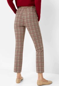 Geruite broek met een beige, rode en bruine checkpatroon. Aansluitend ontwerp, rechte pijpen en een middelhoge tailleband. Gepaard met naaktkleurige flats.