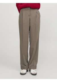 Beige veckade kostymbyxor med skräddarsydd passform, med en jämn yta och uppvikta benslut, kombinerat med vita och grå sneakers.