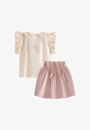 Top crema de manga corta con mangas fruncidas y bordado floral, combinado con una falda recogida rosa claro con cordón trenzado.