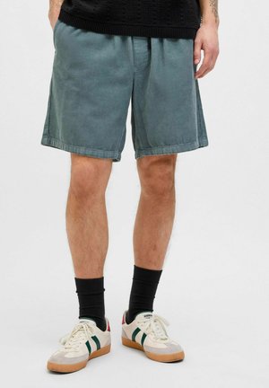 Light gray corduroy shorts with an elastic waistband, side pockets, and a relaxed fit, paired with dark socks and retro sneakers.