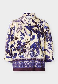 Κρεμ μπλούζα με μπλε και μωβ λουλουδάτα και φυλλώδη μοτίβα, εμπρόσθιο μέρος με κουμπιά, φουσκωτά μανίκια ως το κοντό τρία τέταρτα και στρογγυλεμένη σχεδίαση περιμετρικά στο τελείωμα.