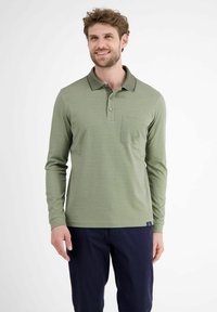 Langærmet polo-shirt i dæmpet grøn, lavet af en bomuldsblanding. Har en krave, tre-knaps placket og en brystlomme med subtil logo-detaljering.
