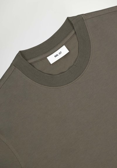 Oliven grøn t-shirt med ribbet rundhals. Glat stof, minimalistisk design, har et mærke med "NN.07" synligt ved kraven.
