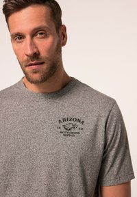 Krátký rukáv šedé heather tričko s černou grafikou orla a textem "Arizona 1880 Motocross Supply" na přední straně.