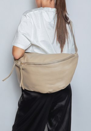 Borsa a tracolla in pelle beige con una texture liscia, chiusura con zip e tracolla. Design arrotondato, forma spaziosa e dettagli hardware minimi.