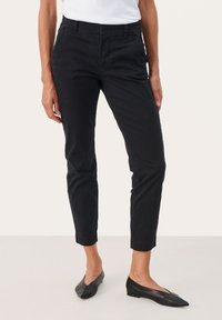 Black, tapered pants made from cotton with a smooth texture. Features two side pockets, a zipper, and a button closure.