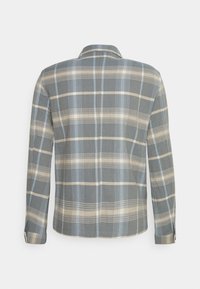 Camisa de manga longa xadrez em tons de cinza e azul, com colarinho abotoado, corte reto e mangas com punho. Textura de tecido suave.