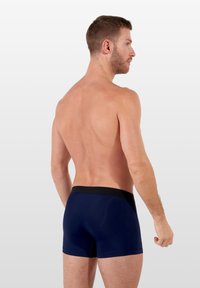 Tmavě modré trenýrky s černým elastickým pasem, hladký povrch, přiléhavý design a krátká délka nohavic, zobrazené zezadu.