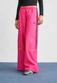 Rózsaszín, bőszárú nadrág könny�ű anyagból, fekete oldalsávokkal és sárga varrással, kényelmes gumis derékrésszel.