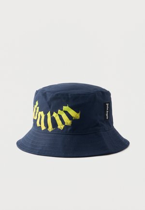Granatowy kapelusz typu bucket z żółtymi literami w stylu gotyckim oraz małą czarną metką z napisem "Palm Angels" po boku.