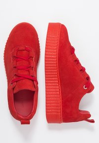Baskets en suédine rouge avec une semelle en caoutchouc texturé, dotées de lacets tissés et d'un design découpé au niveau du talon pour la respirabilité. Forme de bout arrondi.