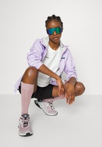 Light purple jacket, white shirt, black shorts, pink knee-high socks, and gray-pink sneakers. Large mirrored sunglasses complete the look.
