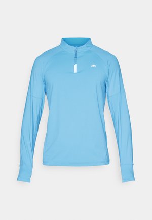 Gaiši zils ilgu piedurkņu tops ar pus-zips apkakli, izgatavots no gludas auduma. Iespējas raglānu piedurknes un mazs logo uz krūškurvja.