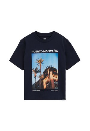 Tricou din bumbac bleumarin cu un grafic central cu palmieri și o clădire, cu textul "PUERTO MONTAÑA" deasupra, în alb. Mâneci scurte.