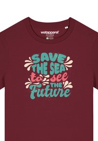 Bordeaux kleurige t-shirt met een ronde hals. Voorkant bevat meerkleurige tekst: "Red de Zee om de Toekomst te Zien," met decoratieve elementen.