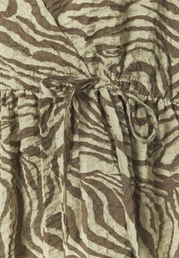 Omklädningsklänning i texturerad tyg med ett mönster av brun och beige zebrastripes, med ett knytbart midjeband för en figursydd siluett.