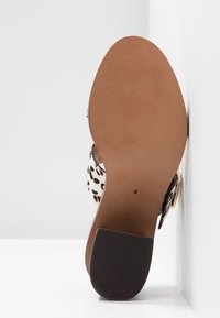 Semelle d’une chaussure à talons hauts pour femme taille 4 avec une bride imprimé léopard et un bout de talon noir texturé.