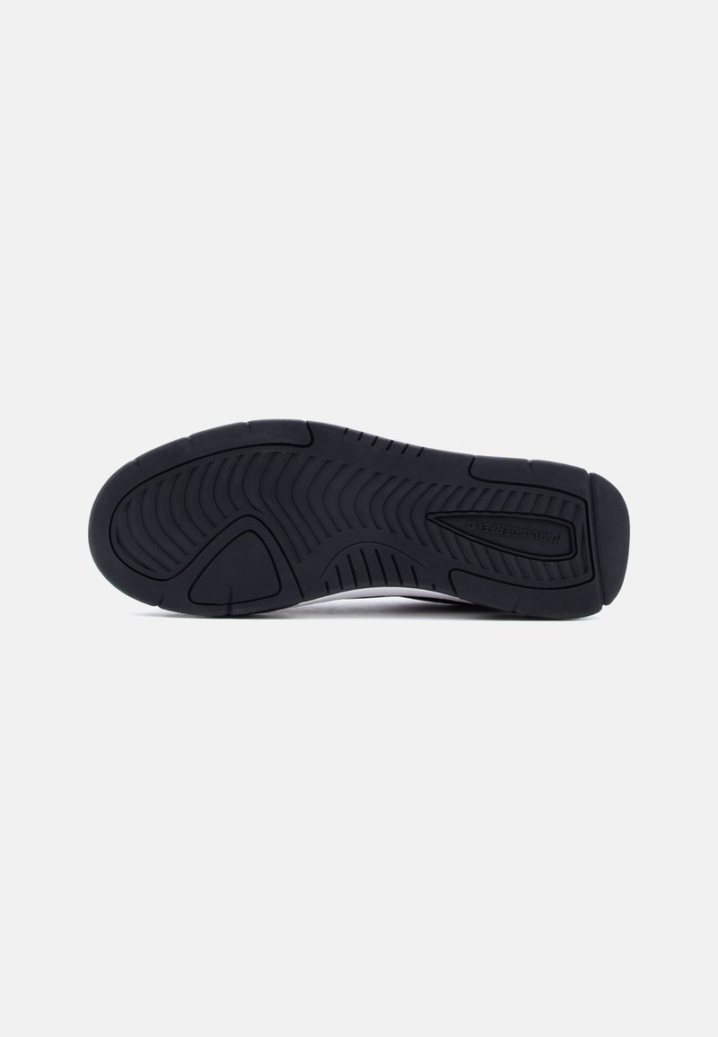 Suela de zapato de goma negra con patrón de banda de rodadura texturizado que presenta surcos curvos y rectos para agarre y flexibilidad.