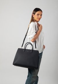 Black leather tote bag with a textured finish, featuring two top handles and a detachable shoulder strap. Gold hardware accents.