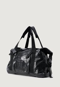 Mala de duffel preta feita de material brilhante, apresentando alças duplas, tiras ajustáveis, um bolso frontal e um patch de logo na lateral.
