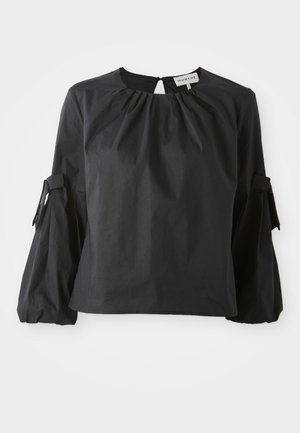Blouse noire à encolure ronde et ouverture en forme de clé. Avec des manches bouffantes ornées de liens et une finition en tissu texturé.